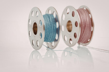 Two spools of thread, one pink and one blue, on a white background