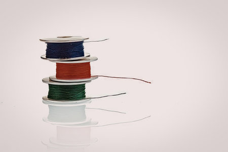 A stack of four spools of colored wire on a white background.