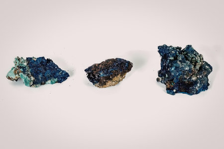 Three mineral specimens with vibrant blue and green colors are arranged on a white background.