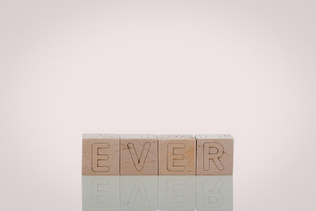A set of wooden blocks with carved letters on them, reflected on a white surface.
