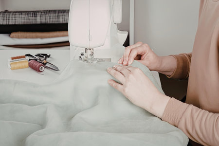 A person is shown working on a sewing machine with a piece of fabric
