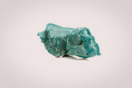 A vibrant green chunk of emerald rock with a rough texture, set against a plain white background.