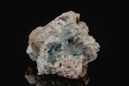 The image features a rough, unpolished crystal with a predominantly white and light blue coloration, set against a stark black background. The crystal's surface is rugged and uneven, showcasing its natural, unrefined state.の写真素材
