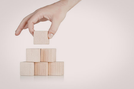 A hand placing a wooden block on top of a stack of blocks