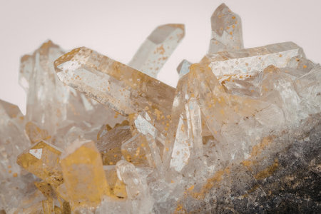 The image features a cluster of golden crystals protruding from a rock, set against a white...