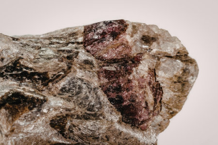 This image presents a detailed view of a raw garnet gemstone, showcasing its natural, unpolished...