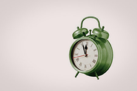 A green metal alarm clock with a white face and red accents, set against a plain white background.