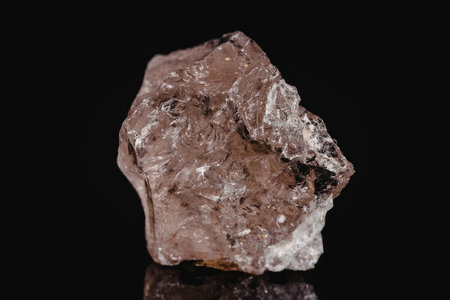A large crystal with a rough surface and a pinkish color is displayed against a black background.