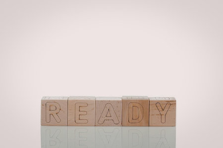 A set of wooden blocks arranged to spell out the word 'READY' on a reflective surface