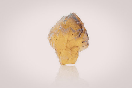 A large yellow crystal or gemstone on a white background, reflecting light and showcasing its...