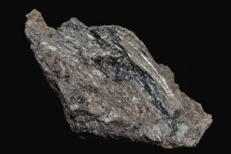 A large gray rock with a rough texture and jagged edges is displayed against a black background. The...