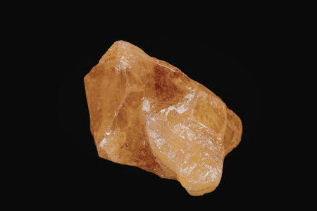 A large orange rock with a rough texture is displayed on a black background. The rock has a glossy...