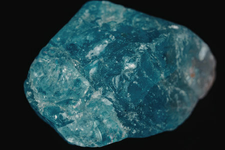 A close-up image of a large teal colored mineral rock with a rough texture on a black background.