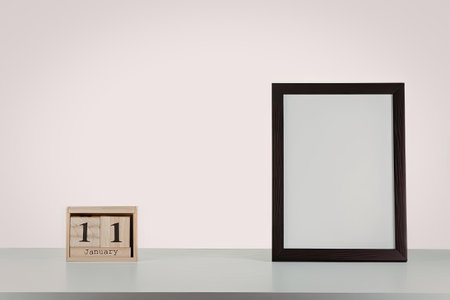 A picture frame and a wooden block calendar on a deskの写真素材