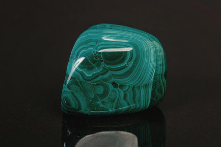 A close-up of a polished malachite stone showcasing its vibrant green color and distinctive banded...