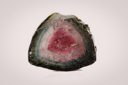 A close-up image of a watermelon tourmaline gemstone slice, showcasing its vibrant pink and green...