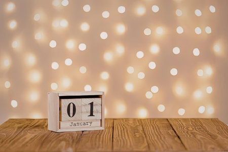 A small white block with a black number 01 on it sits on a wooden table in front of a wall with many...
