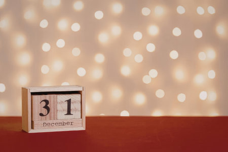 A small wooden calendar displaying the date 31 on a red surface with a blurred background of lights.の写真素材
