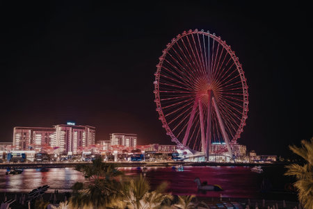 a large ferris wheel lit up at night with a city skyline in the background