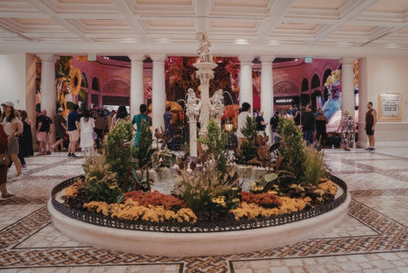 A large foyer with a beautiful fountain and many people walking around, the fountain has a statue in...
