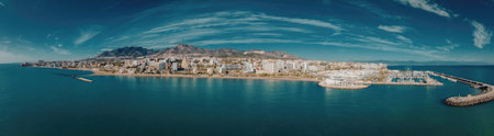 A panoramic view of a coastal town with a large body of water and a mountain in the background