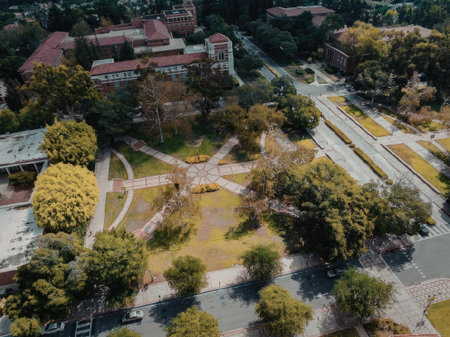 An aerial view of a park with buildings, trees, and walkways. The park has a large grassy area with...