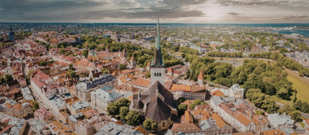 A panoramic aerial view of a historic old town with red-tiled roofs and a prominent church steeple,...