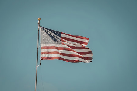 The American flag waving in the wind against a clear blue sky.