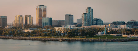 A panoramic view of a city skyline with tall buildings and skyscrapers by a body of water during sunset.の写真素材