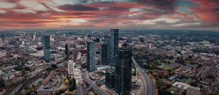 A panoramic view of a city during sunset, featuring modern skyscrapers and a vibrant sky with hues...