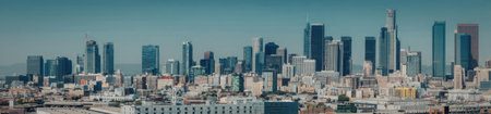 A panoramic view of a city skyline featuring modern skyscrapers and buildings under a clear blue...
