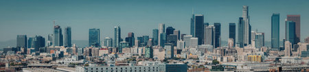 A panoramic view of a city skyline featuring modern skyscrapers and buildings under a clear blue...