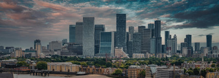 A panoramic view of a city skyline during sunset, showcasing modern skyscrapers and a vibrant cloudy...