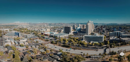 A panoramic view of a city with modern buildings, a highway, and a clear blue sky.