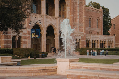 A large brick building with a fountain in the foreground, surrounded by a well-manicured lawn and...