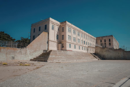 A large, tan-colored historic building with a prominent staircase leading up to it. The building...