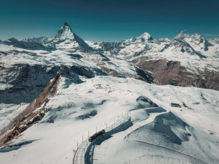 A breathtaking view of snow-covered mountains with a train on a track in the foreground, set against...
