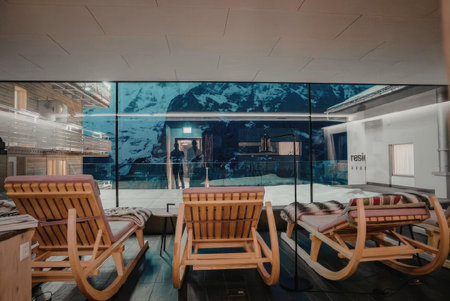 A seating area with wooden chairs facing a large window that overlooks a snowy mountain landscape.の写真素材