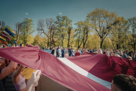 A crowd of people holding a large Danish flag in a parkの写真素材