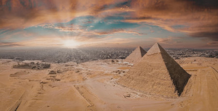 The image depicts the Pyramids of Giza, Egypt, set against a vibrant sunset sky with orange and blue...