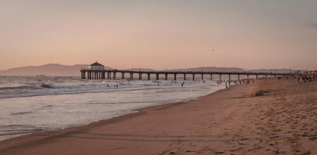 A serene beach scene at sunset featuring a long pier extending into the oceanの写真素材