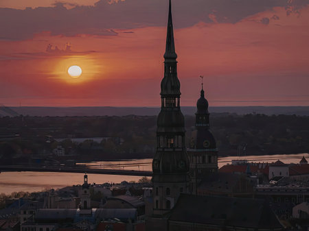 A serene sunset over a city skyline featuring two prominent towers, with a body of water in the...