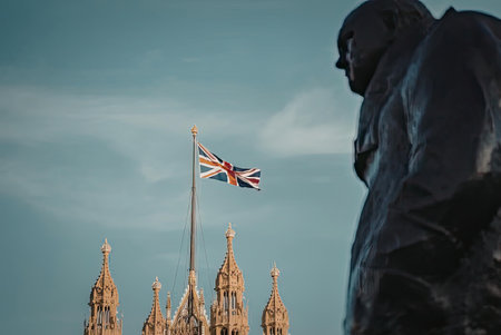 A statue stands in the foreground with the British Parliament building and flag in the background.