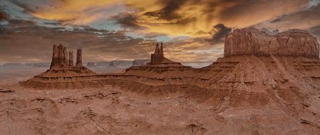 A panoramic view of Monument Valley at sunset, showcasing iconic rock formations and a vibrant...