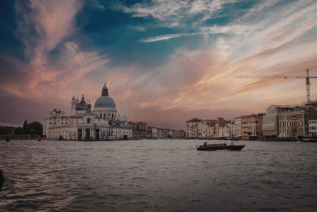 A serene sunset scene over a Venetian waterway, featuring a prominent white building with a large...