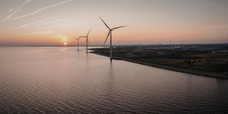 A serene landscape featuring wind turbines standing tall over a body of water during a breathtaking...