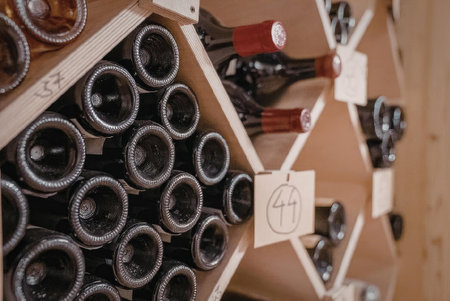 A close-up view of wine bottles stored in a wooden wine cellar with a tag hanging from the rack.