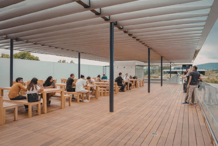 a large outdoor deck with a slanted roof, where people are sitting at wooden tables and eating