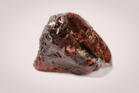 a large red gemstone on a white background, possibly a garnet or ruby, with a rough, unpolished...