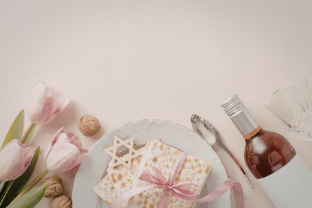 A plate with matzo, a bottle of wine, and pink tulips on a pastel background